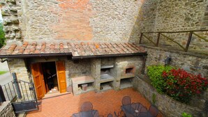 A stone building with a tiled roof, outdoor seating area, and a small brick oven. - A very old small stone hamlet set in a panoramic position a few km from the city of Arezzo. Endowed (Palazzo del Pero)