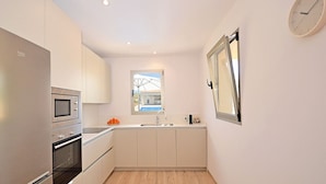 A compact kitchen with a built-in oven, microwave, and sink.