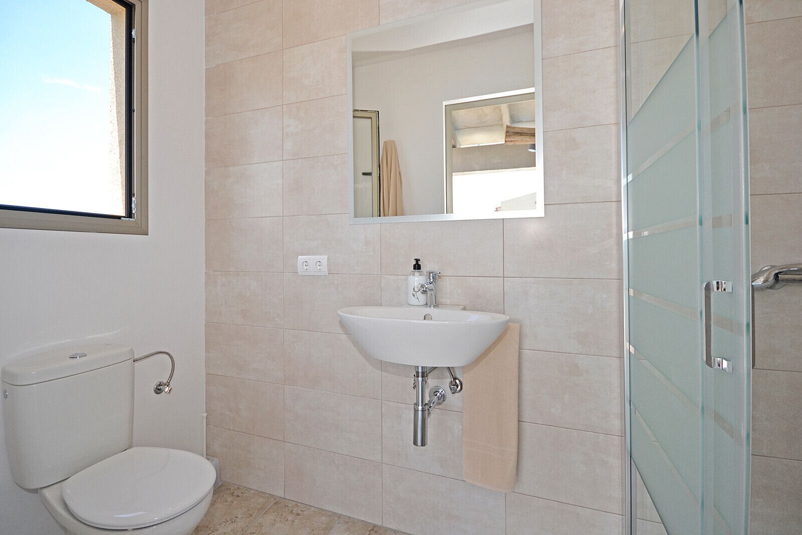 Ein Badezimmer mit Toilette, Waschbecken und Duschabtrennung aus Glas.