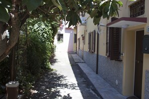 A narrow alleyway with a tree on one side and a building with a door and window on the other. - Nice Apartment in an English Style Building On the First Floor, With air Conditioning, Wifi and Sewing (Bologna)