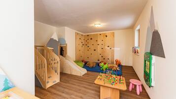 Un salón infantil con una pared de escalar, un tobogán y una mesa de juegos.