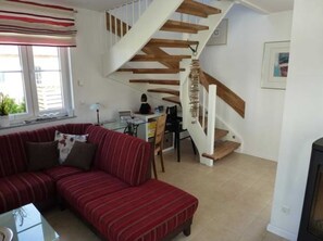 Una sala de estar con un sofá rojo, una mesa de comedor y una escalera con vigas de madera.