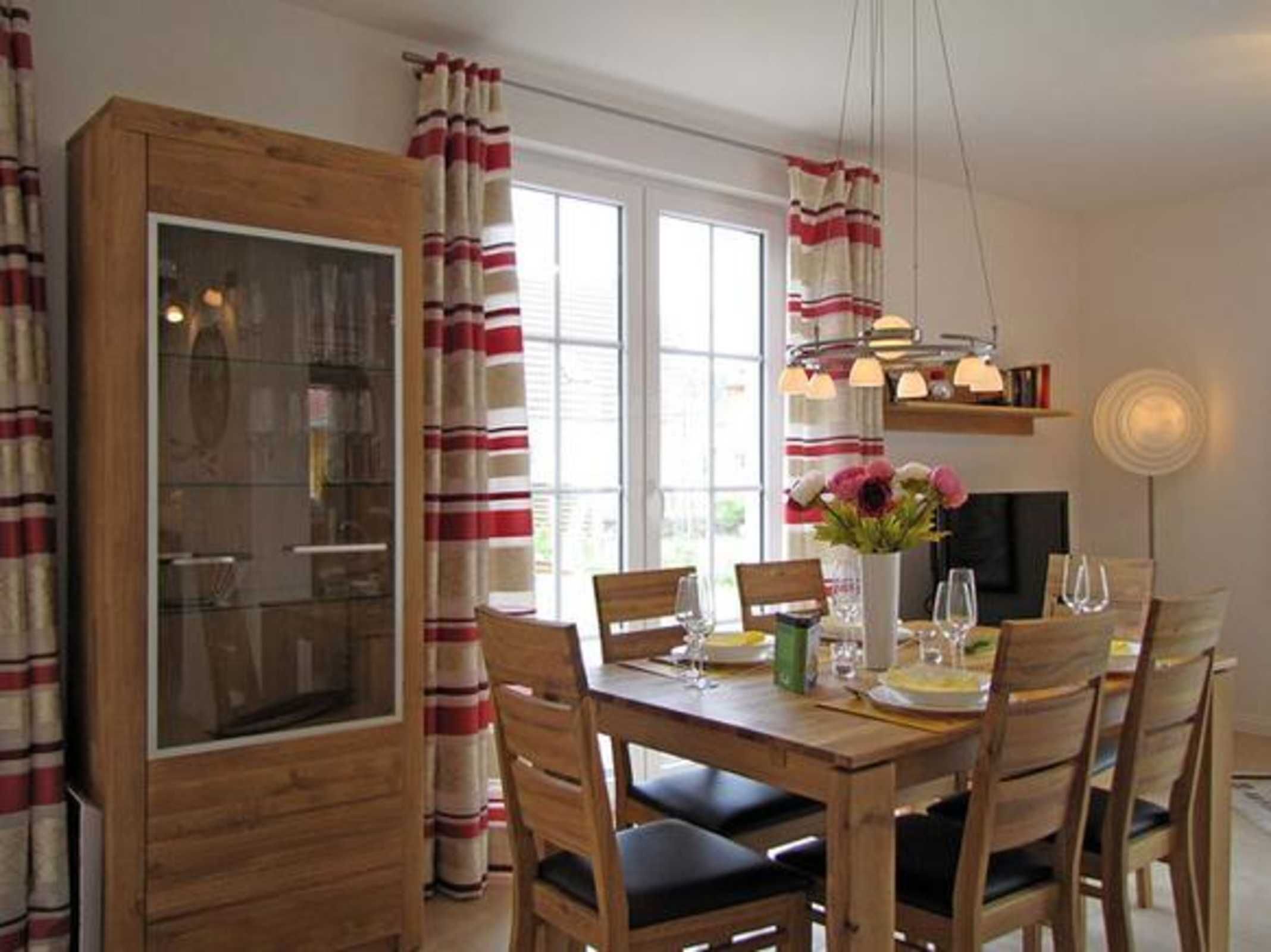 A dining area with a wooden table, chairs, and a vase with flowers.