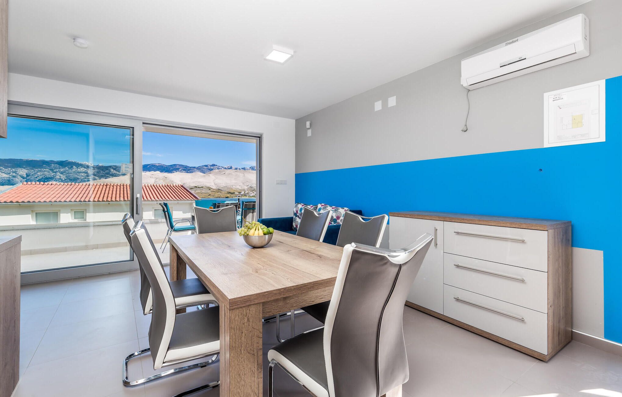 A modern kitchen with a wooden table, white cabinets, and a blue accent wall.
