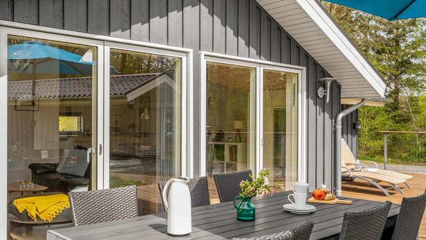Een buiten eethoek met een tafel, stoelen, een groene vaas en een parasol.