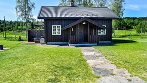 Un chalet rustique en bois, doté d’un toit en tuiles, d’un chemin de pierre menant à l’entrée et d’une cour clôturée.