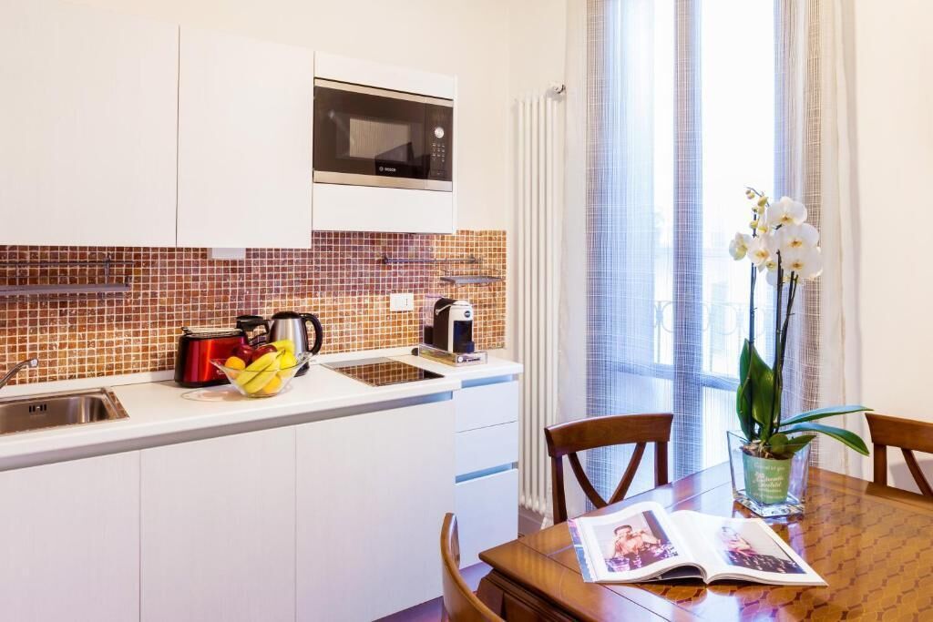 A modern kitchen with a microwave, sink, and a dining area with a table and chairs.