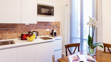 A modern kitchen with a microwave, sink, and a dining area with a table and chairs.