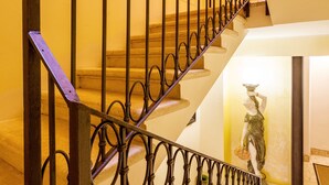 A staircase with ornate metal railings and a patterned carpet at the bottom. - Residenza Vescovado (Vicenza)