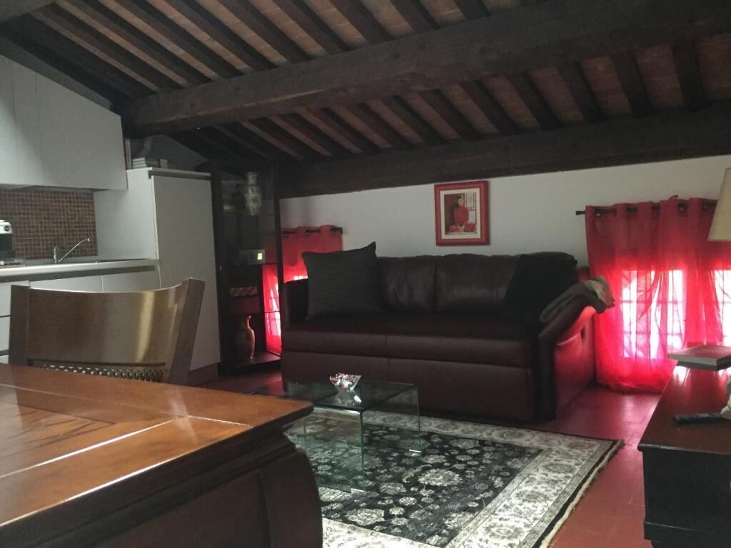 A living room with a wooden dining table, a sofa, a coffee table, and a red curtain.