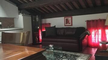 A living room with a wooden dining table, a sofa, a coffee table, and a red curtain.