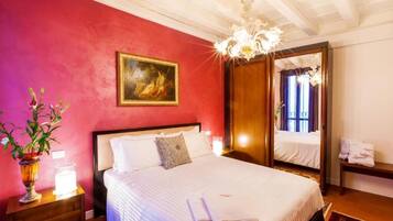Ein Hotelzimmer mit einem großen Bett, einem Gemälde an der Wand, einer Kristallleuchtre und einem Spiegel.