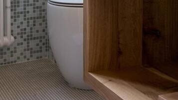 Ein Badezimmer mit Toilette, Toilettenpapier, einem Holzwaschtisch und einer gefliesten Wand.