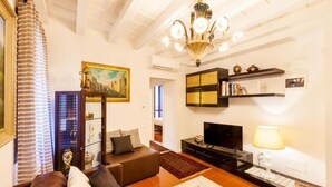 A living room with a sofa, television, bookshelf, and a chandelier. - Residenza Vescovado (Vicenza)