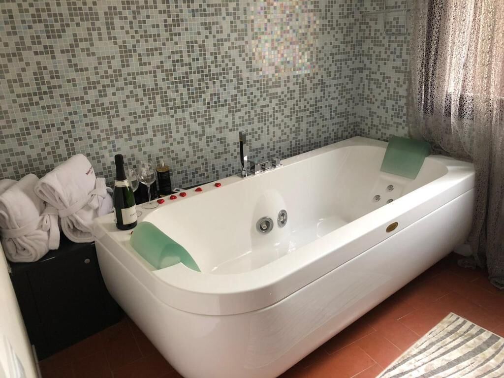 A bathroom with a white bathtub, a tiled wall, and a towel rack with towels.