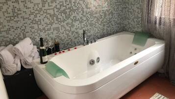 A bathroom with a white bathtub, a tiled wall, and a towel rack with towels.
