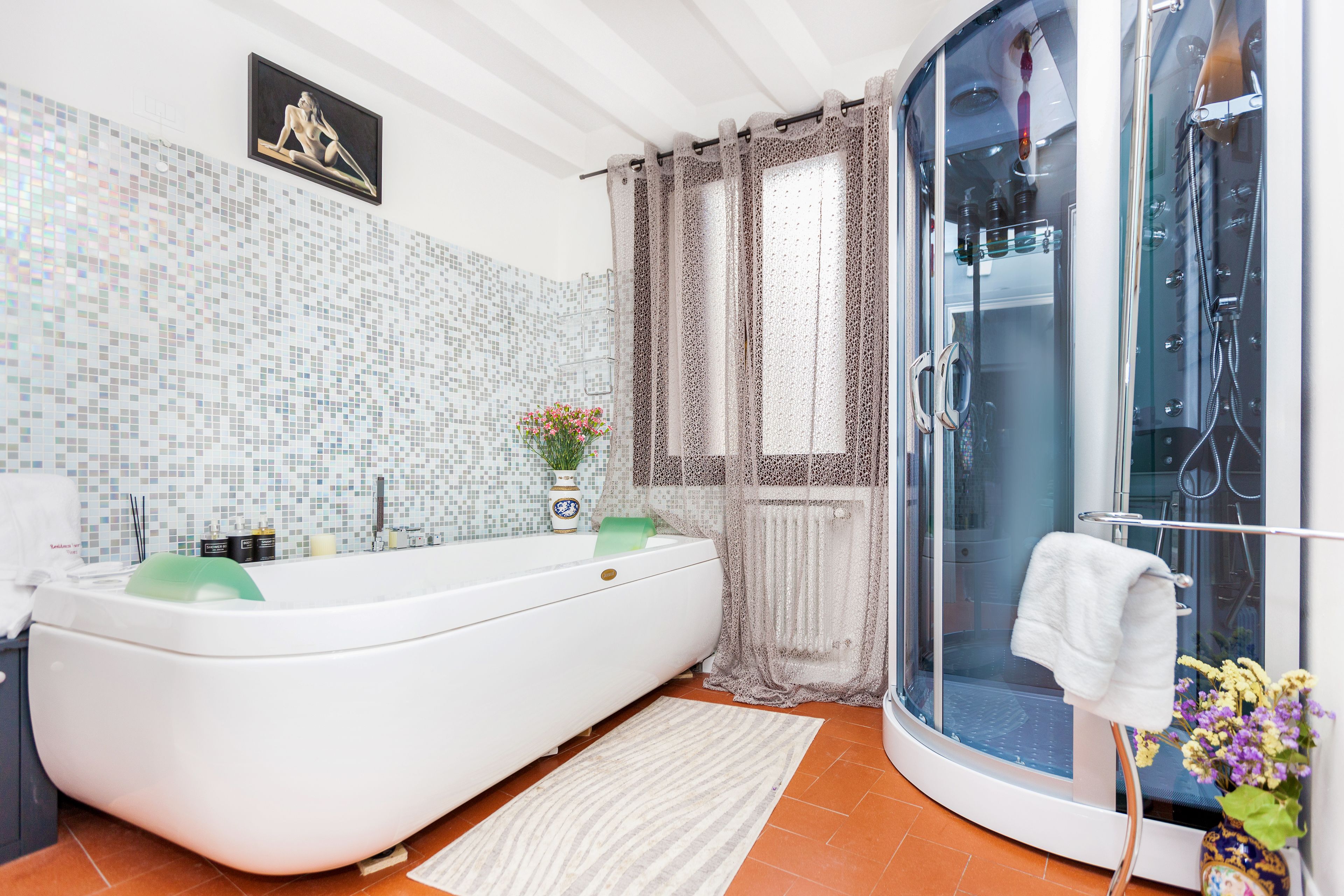 Une salle de bain moderne avec une baignoire sur pieds, une douche à parois de verre et un mur recouvert de mosaïques.