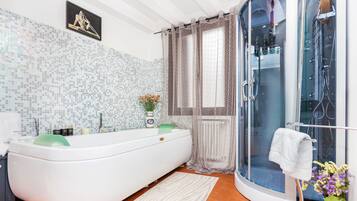 Une salle de bain moderne avec une baignoire sur pieds, une douche à parois de verre et un mur recouvert de mosaïques.