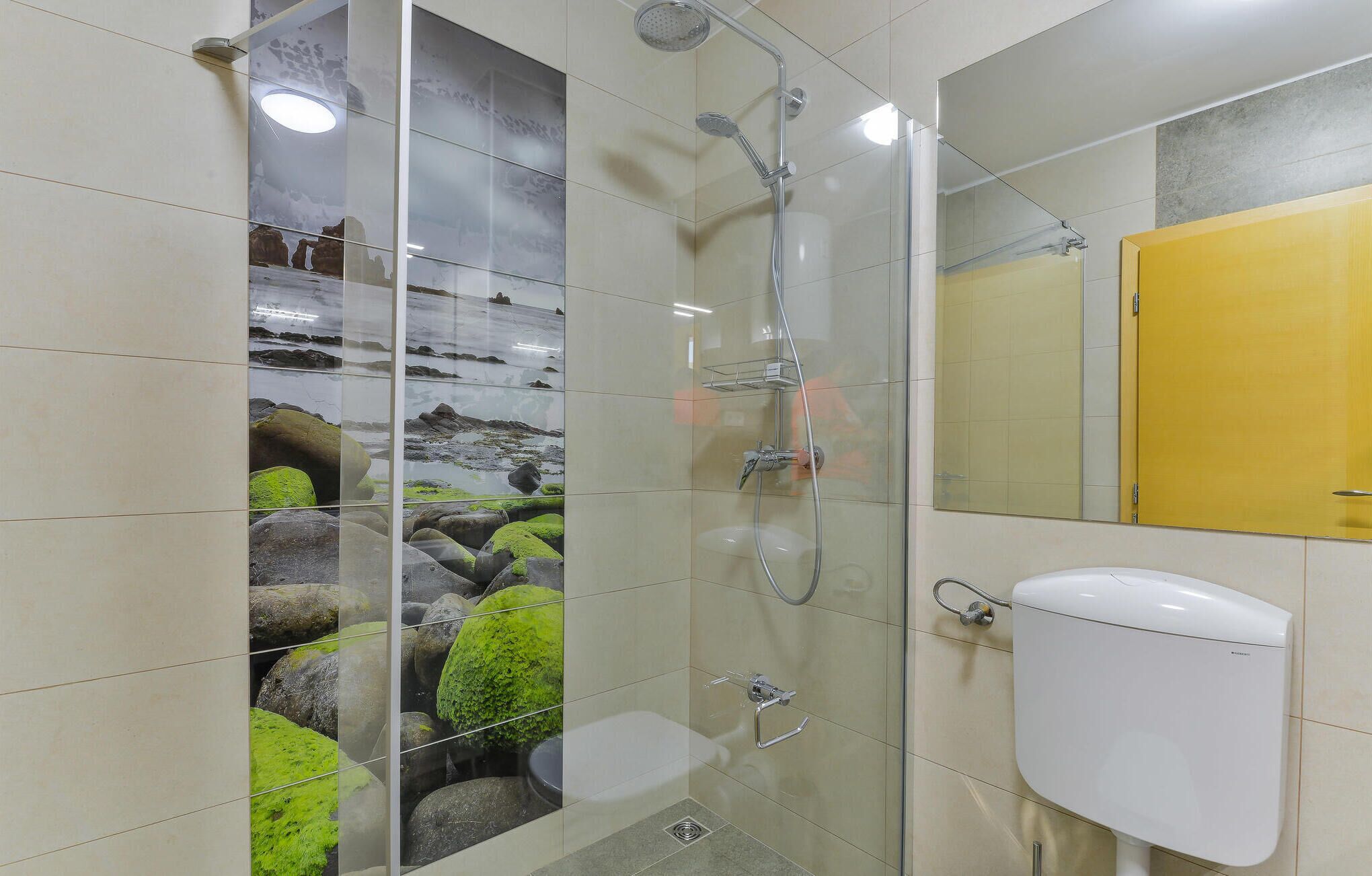 Une salle de bain avec une douche à parois de verre, des toilettes blanches et un meuble jaune.