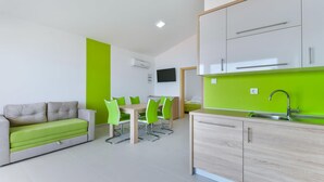 A modern kitchen with a green backsplash, a dining area with a green table and chairs, and a sofa with green cushions. - Nice apartment in Pag with house sea view (Pag)