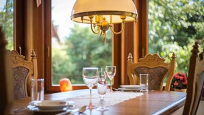 Een eettafel gedekt met glazen en borden, een lamp en uitzicht op groen.