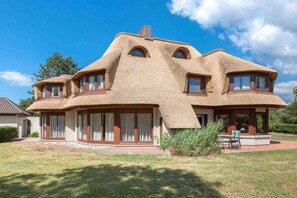 Ein Haus mit einem einzigartigen architektonischen Stil, erkennbar an den gewölbten, strohgedeckten Dächern und den großen Fenstern.