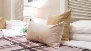 Quarto de hotel com cama, almofadas, abajur e um quadro na parede.