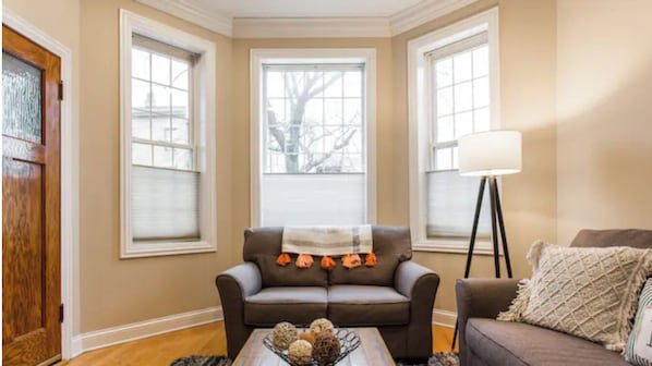 A living room with a brown sofa, a coffee table with decorative items, and a floor lamp.