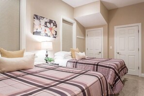 A bedroom with two beds, a nightstand, a lamp, and a floral artwork on the wall.