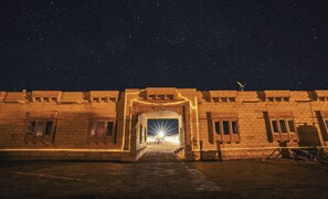 A starry night sky above a building entrance with a bright light at the end of a pathway. - Dynasty Desert Camp (Jaisalmer)