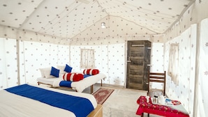 A room with a bed, a table with a red tablecloth, and a wooden door. - Dynasty Desert Camp (Jaisalmer)
