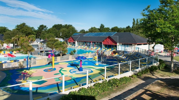 A swimming pool area with colorful play structures and lounge chairs.