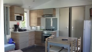 A compact kitchen with a microwave, stove, oven, and a small dining table with chairs.