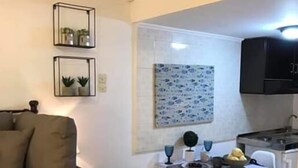 Un espacio habitable compacto con sofá, mesa de comedor y zona de cocina.