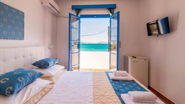 Un dormitorio con cama, televisión y vista al mar.