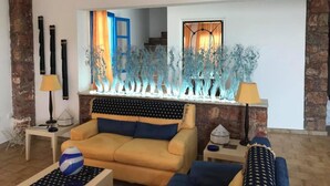 Una sala de estar con un sofá, una mesa de centro y objetos decorativos. Se observa una escalera al fondo.