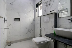 A modern bathroom with a marble floor, a white toilet, a black countertop with a sink, and a mirror above the sink. - Hotel De Hocks Deluxe (New Delhi)