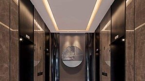 A modern elevator with a sleek design, featuring a circular wall art piece and a minimalist light fixture.