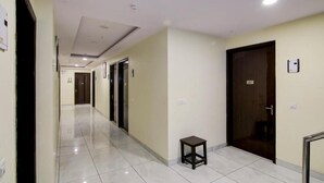A hotel corridor with a tiled floor, a small table, and doors numbered 207 and 208.