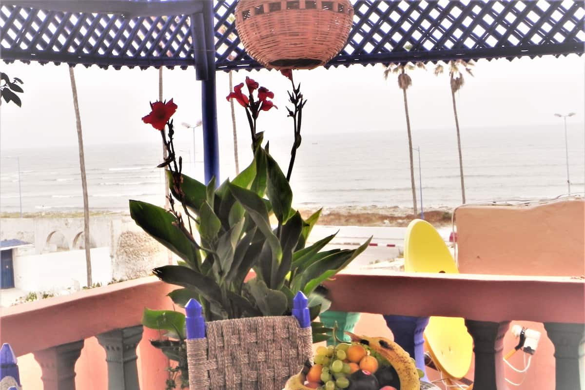Ein Balkon mit einem Blumentopf, einer Obstschale und Blick aufs Meer.