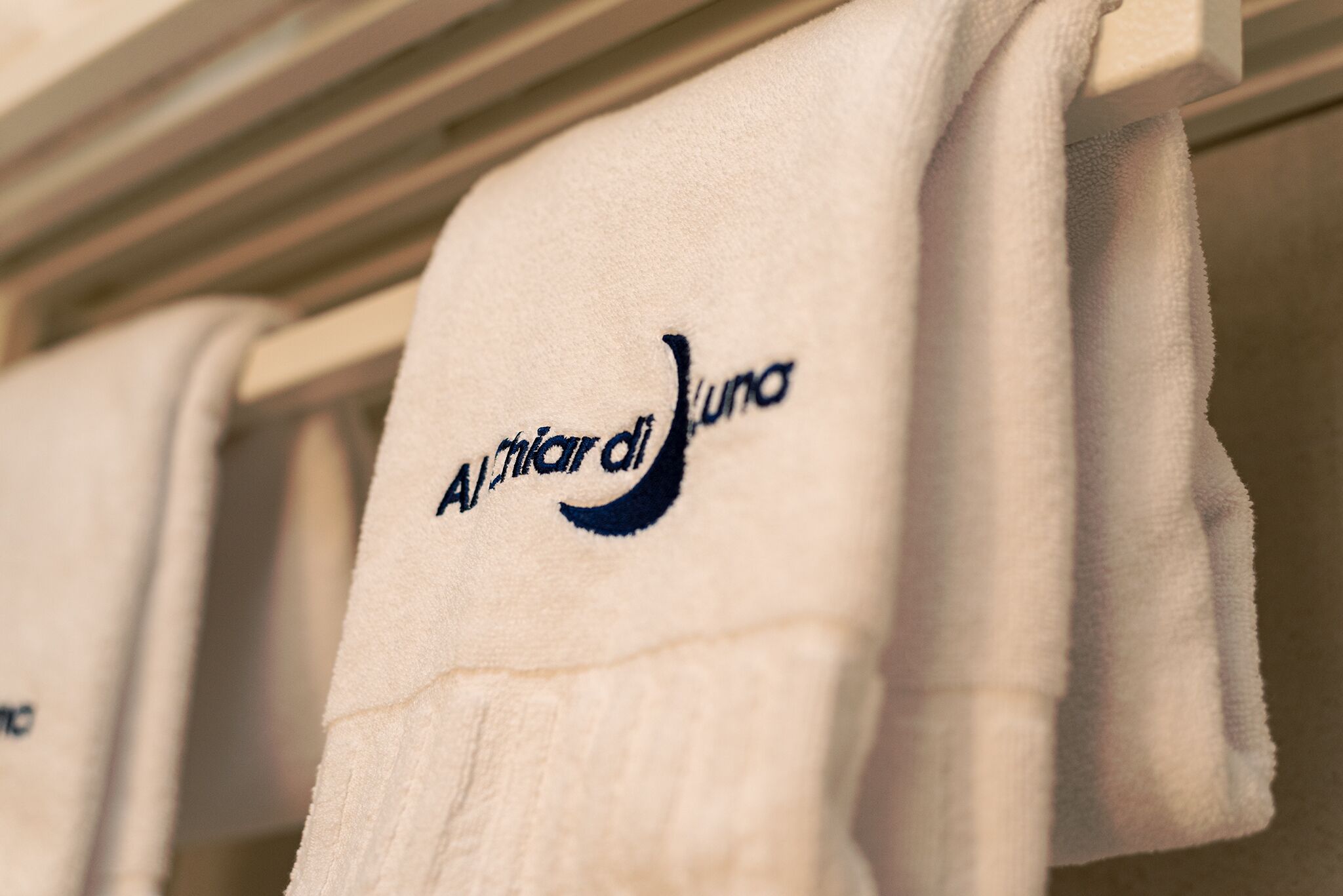 A white towel with the logo "Alitalia del Luna" hanging on a rack.