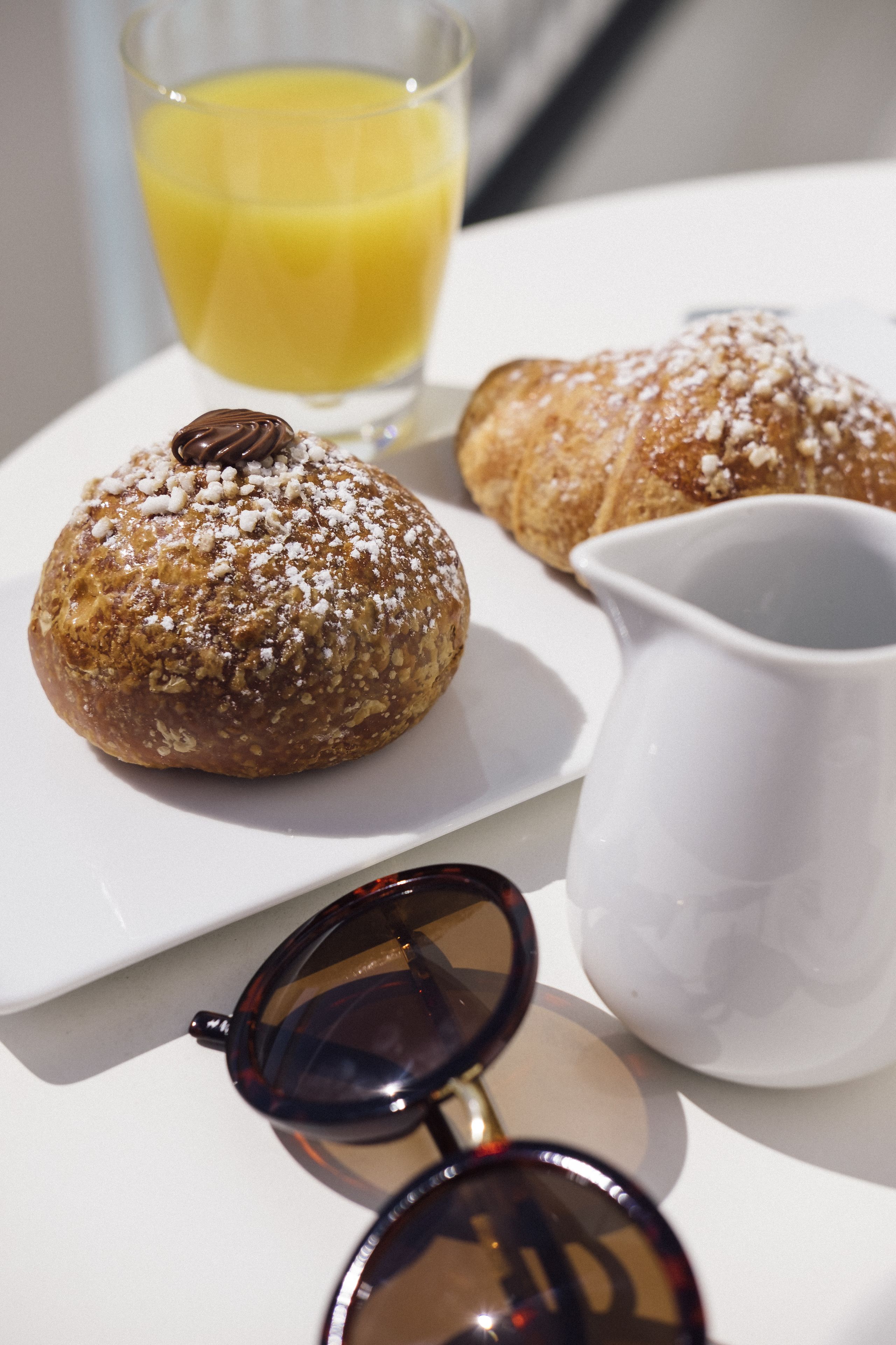 A table with pastries, a glass of orange juice, and a pitcher.
