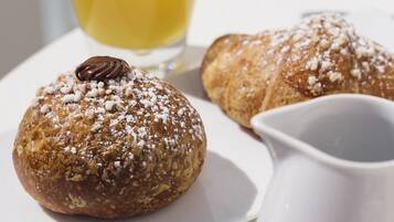 A table with pastries, a glass of orange juice, and a pitcher.
