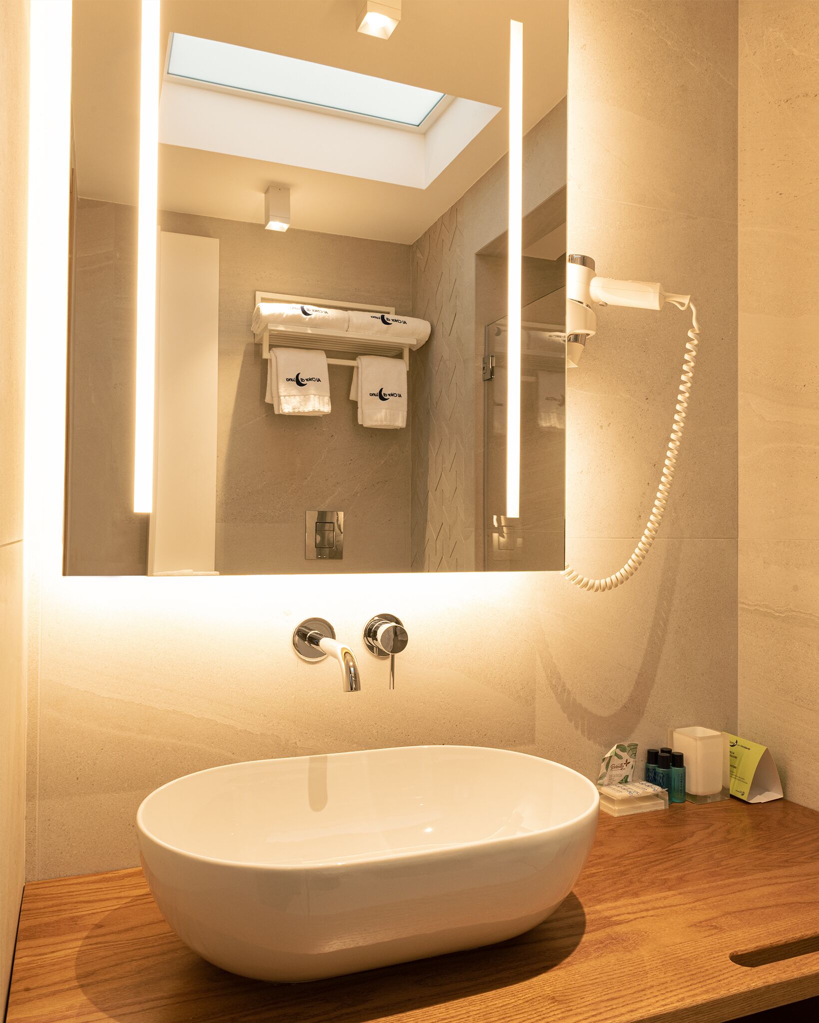 Un bagno moderno con un ampio lavabo ovale, uno specchio e un lucernario.