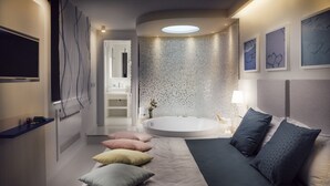 A modern bedroom with a large bed, a round bathtub, and a TV on the wall. - Al Chiar di Luna (Monte di Procida)