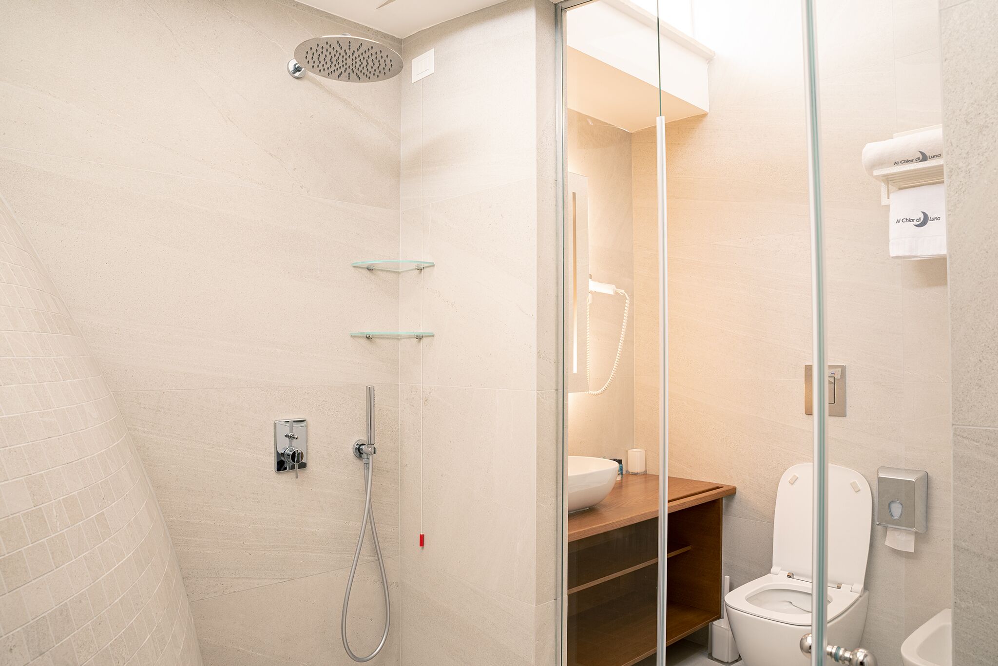 Ein modernes Badezimmer mit einer Duschkabine, einem hölzernen Waschtisch und einer weißen Toilette.