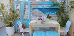 A rustic outdoor seating area with a table, chairs, and potted plants. - kastro hotel (Skiathos)