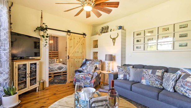 A cozy living room with a wooden ceiling fan, a sofa, a coffee table with drinks, and a TV on a cabinet. - Walk to Dtwn Shops & Eats: Sturgeon Bay Retreat (Sturgeon Bay)