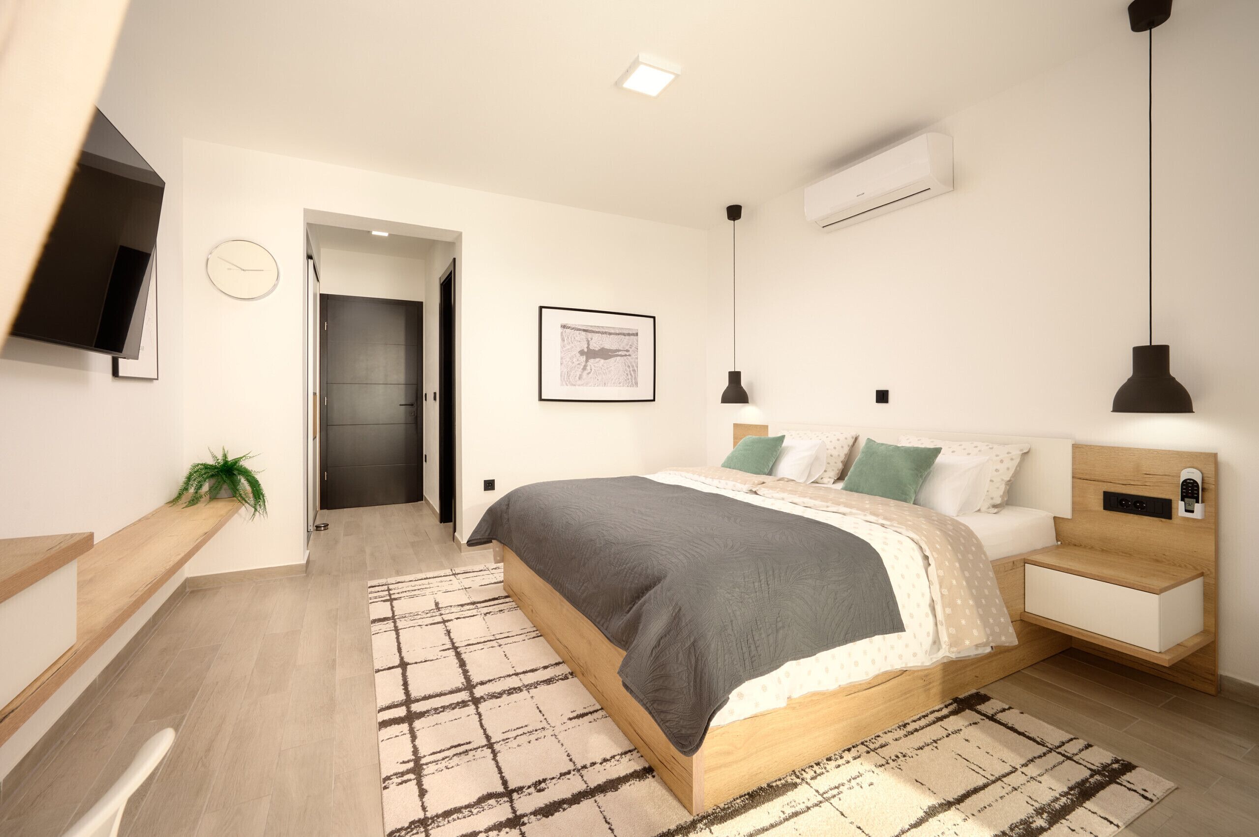 Une chambre moderne équipée d’un lit, de tables de chevet, d’un téléviseur et d’un appareil de climatisation.