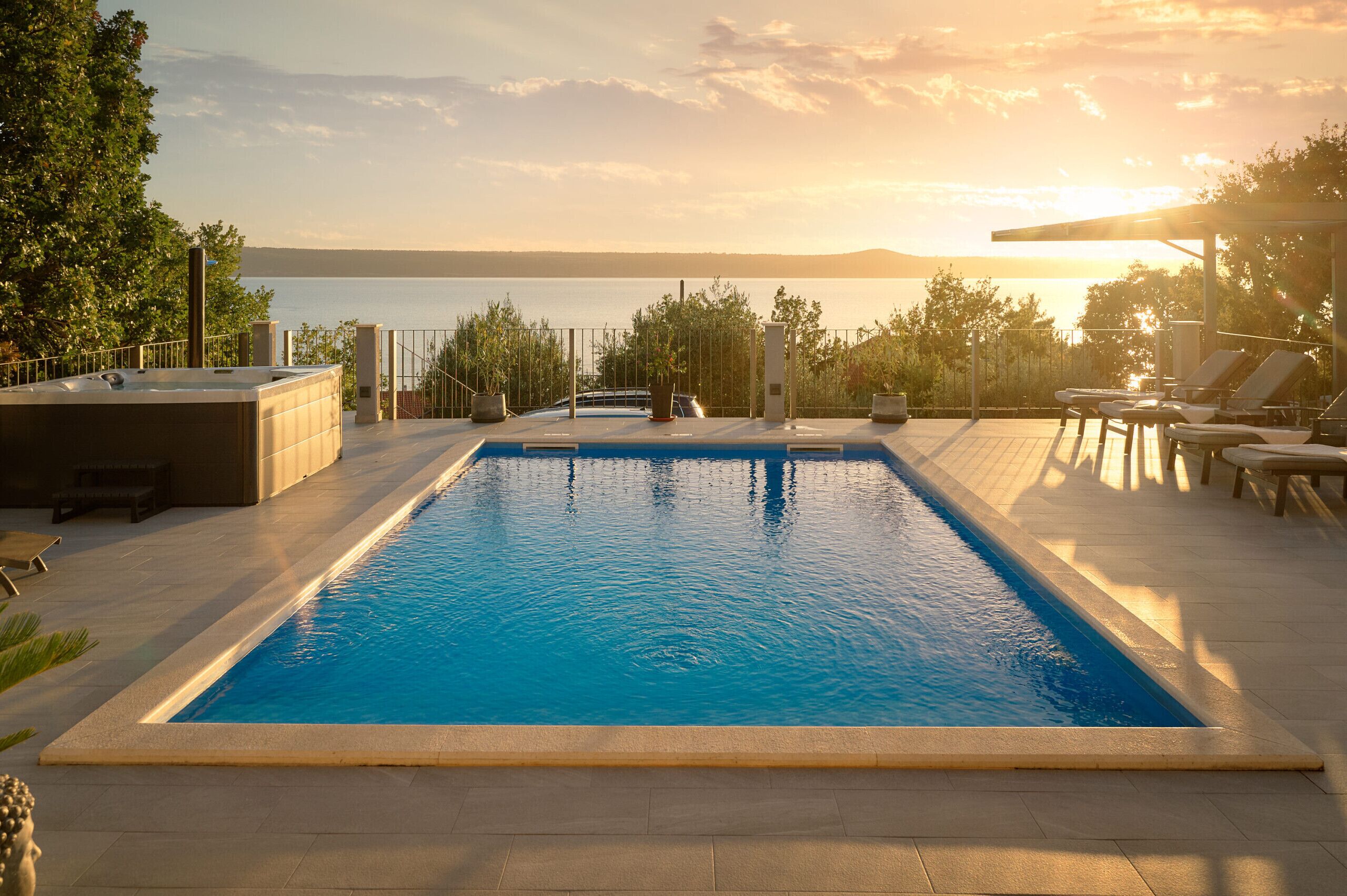 Una piscina rectangular con vistas al mar y montañas al fondo.